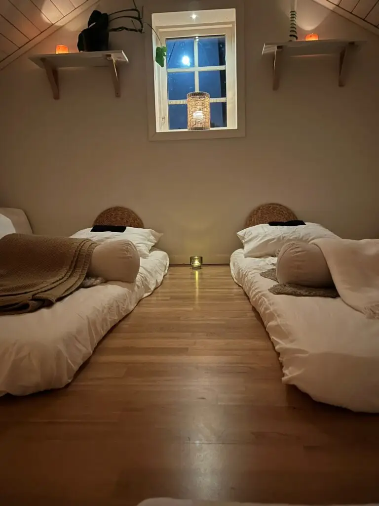 Två madrasser i ett mysigt, dämpat rum med varma ljuskällor.